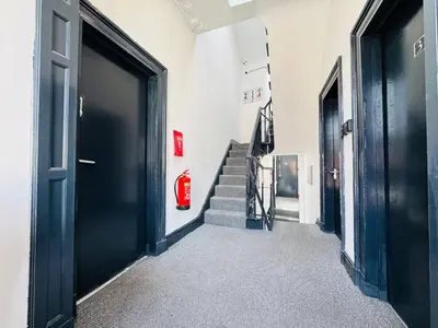 a hallway with black doors and stairs with a fire hydrant at Pembroke Place Private Room 5B in Liverpool