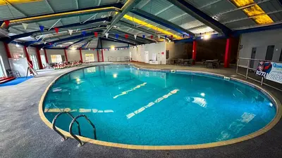 a large swimming pool with blue water in a building at Hobbit - House Of The Owl - Luxury Lodge with Pool in Longridge
