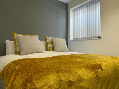a bedroom with a large bed with a yellow blanket at Full Private House Sleeping Up To 18 - Close To Seafront in Blackpool