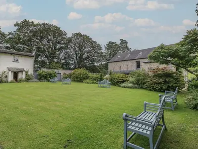 a yard with three blue benches in the grass at The Gameskeepers Cottage in Grange Over Sands