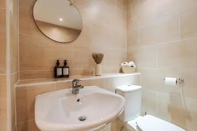 a bathroom with a sink and a toilet and a mirror at Premium 10-Room Contractor Accommodation Central Location in Liverpool