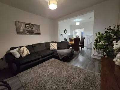a living room with a black couch and a table at Room 1 Shared House 3 min from Stadium in Liverpool