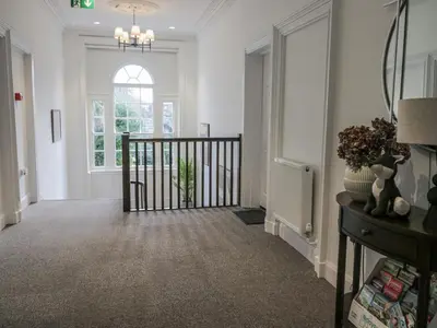 a hallway with white walls and a staircase with a window at Ullswater in Ulverston