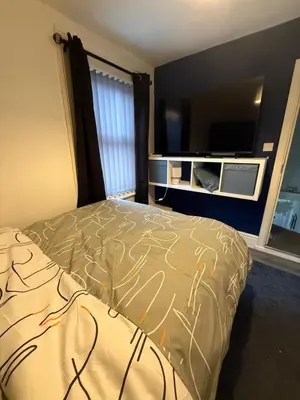 a bedroom with a bed and a flat screen tv at Home From Home in Liverpool