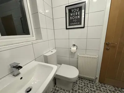 a bathroom with a toilet and a sink and a sign at Morton suite in Litherland