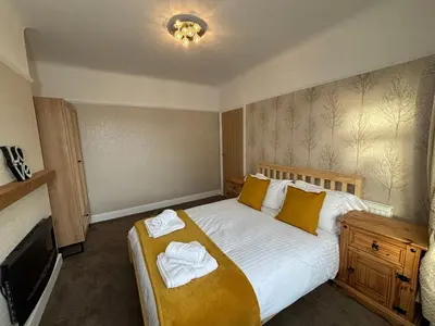 a bedroom with a large bed with towels on it at Henry suite in Litherland