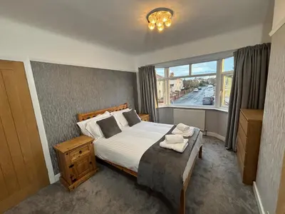 a bedroom with a large bed and a window at Thirlmere Stay in Litherland