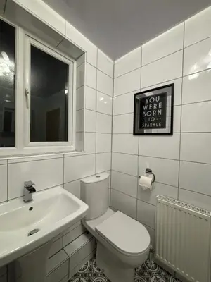 a white bathroom with a toilet and a sink at Thirlmere Stay in Litherland