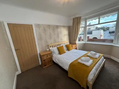a bedroom with a bed with yellow sheets and a window at Thirlmere Stay in Litherland