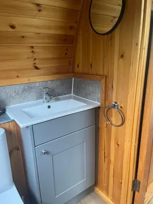 a bathroom with a white sink in a wooden wall at Mill House Farm Pods - Lapwing Lodge in Pilling
