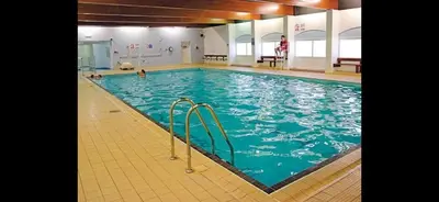 a large swimming pool with blue water in a building at Happy Go Lucky Lodge in Middleton