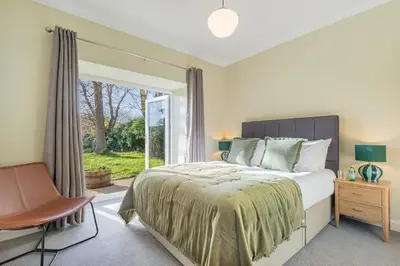 a bedroom with a bed and a chair and a window at Royal Oak Barn - Cartmel, Sleeps 8 NEW in Cartmel