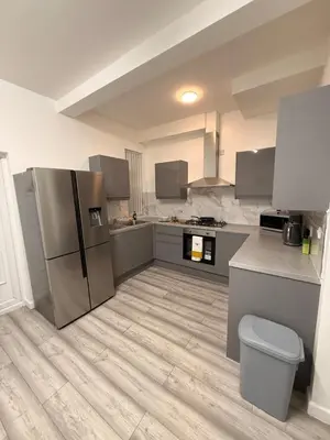 a kitchen with a stainless steel refrigerator and cabinets at Stylish Dream Home with 4 En-Suite Bedrooms in Liverpool