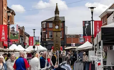 a crowd of people walking down a street with a clock tower at Comfy Ormskirk Family Stay by PolkaStays in Ormskirk
