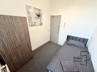 a bedroom with a bed and a wooden cabinet at Spacious Ormskirk Contractor Stay by PolkaStays in Ormskirk