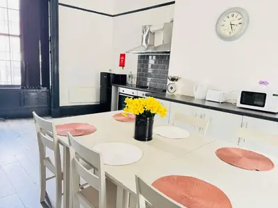 a kitchen with a table with chairs and a clock at 12B Classy Bedroom in a Shared home at Pembroke in Liverpool