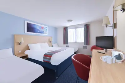 a hotel room with two beds and a chair at Travelodge Burton M6 Northbound in Holme