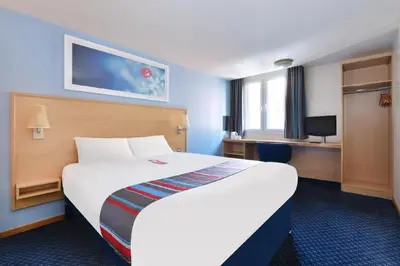 a hotel room with a large bed and a desk at Travelodge Barrow In Furness in Barrow in Furness