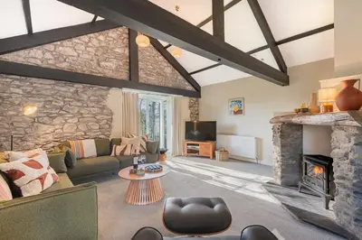 a living room with a fireplace and a stone wall at The Royal Oak Barn Cartmel - Sleeps 4 in Cartmel