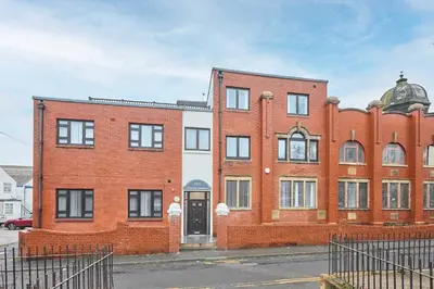 a red brick building with a black door at Host & Stay - Illumination Suite in Blackpool