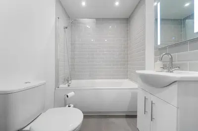 a white bathroom with a tub and a toilet and a sink at Large 4BR House - Sleeps 7 - Long Stays Great Location in Litherland