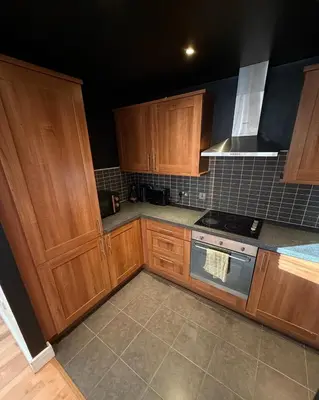 a kitchen with wooden cabinets and a stove top oven at 2-Bed City View with Balcony Liverpool by StaySavvy Accommodation in Liverpool