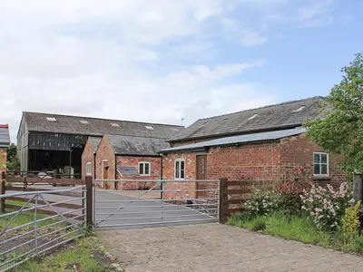 a brick barn with a gate in front of it at The Stable in Burscough