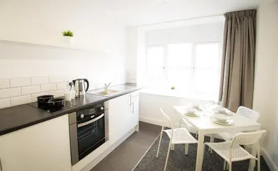 a kitchen with a table and a white table and chairs at Fox Street Apartments in Liverpool