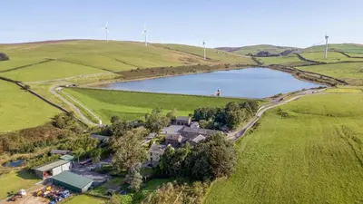 an aerial view of a house in a field with a lake at Thimble Cottage in Ulverston