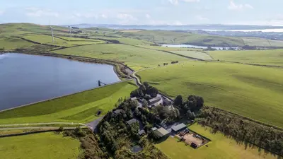 an aerial view of a house in a field next to a lake at Woodside Barn in Ulverston