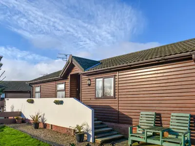a house with two green chairs in front of it at Tranquillity in Millom