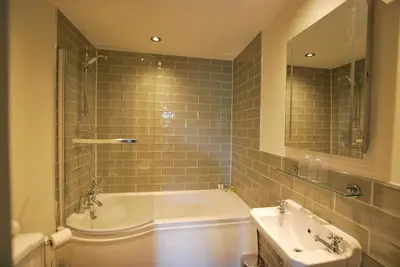 a bathroom with a tub and a sink and a mirror at Ye Olde Fighting Cocks in Arnside