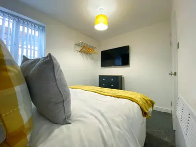 a bedroom with a bed with a yellow blanket at Kensington Suite Sasco Apartments in Blackpool