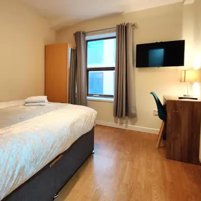 a bedroom with a bed and a tv and a window at Liverpool City Centre Private Rooms including smart TVs - with Shared Bathroom in Liverpool