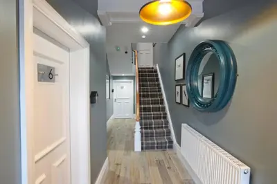 a hallway with a staircase with a blue mirror at Blackbird Luxury Accommodation Room 10 in Blackpool