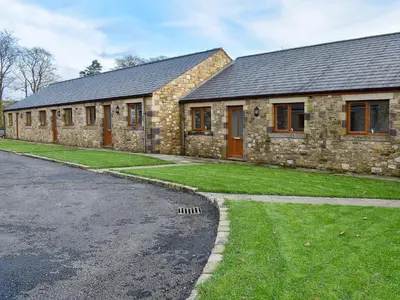 a stone house with a grass yard next to a street at Four Dorchester Drive - Uk32042 in Inglewhite