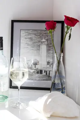 a bottle of wine and a vase with a rose and a glass at Finest Retreats - Walney Island Lighthouse in Rampside