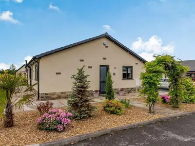 a house with trees and flowers in front of it at Willows Cottage in Blackburn