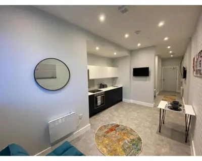 a living room with a table and a mirror on the wall at Kempston Suites Liverpool Apartment 2 in Liverpool