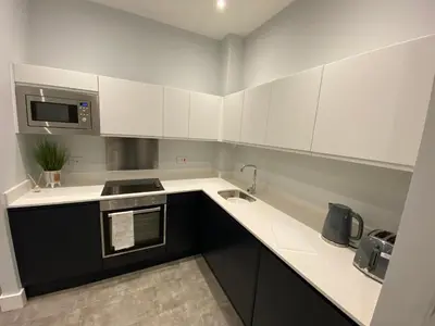 a kitchen with white cabinets and a sink at Kempston Suites Liverpool Apartment 6 in Liverpool