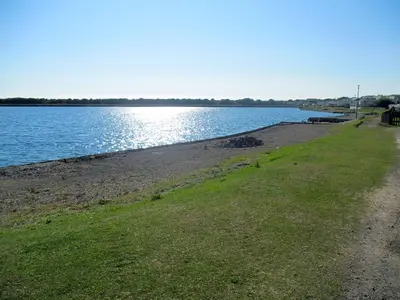 a beach with a path next to a body of water at Plot 188D Lakeside Cabin, Wyldecrest, Millom in Millom