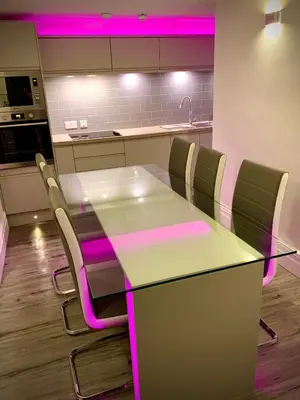 a kitchen with a table and chairs with pink lighting at Saltrock luxury apartment in Blackpool