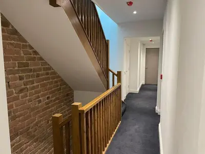 a hallway with a staircase and a brick wall at The Royal Crest in Liverpool
