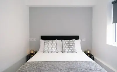 a bedroom with a bed with white sheets and pillows at The Kop End Hotel by Serviced Living Liverpool in Liverpool