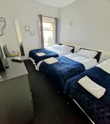 a hotel room with two beds and a desk at The Bosworth House Hotel in Blackpool