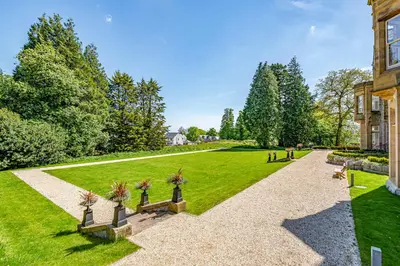a garden with benches in front of a building at The Elizabeth Suite Stone Cross Mansion in Ulverston
