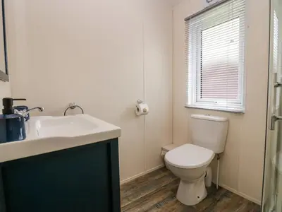 a bathroom with a toilet and a sink and a window at Lakeland Dream South Lakeland Leisure Lodge in Carnforth
