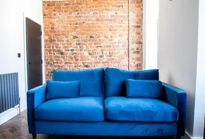 a blue couch in front of a brick wall at Withnell Stays - Apartment Five in Blackpool