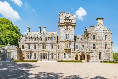 a large stone building with a clock tower on it at The Kathleen Suite Stone Cross Mansion in Ulverston