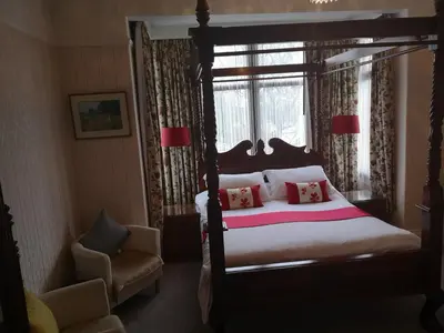 a bedroom with a bed and a chair and a window at East Mount House in Barrow in Furness